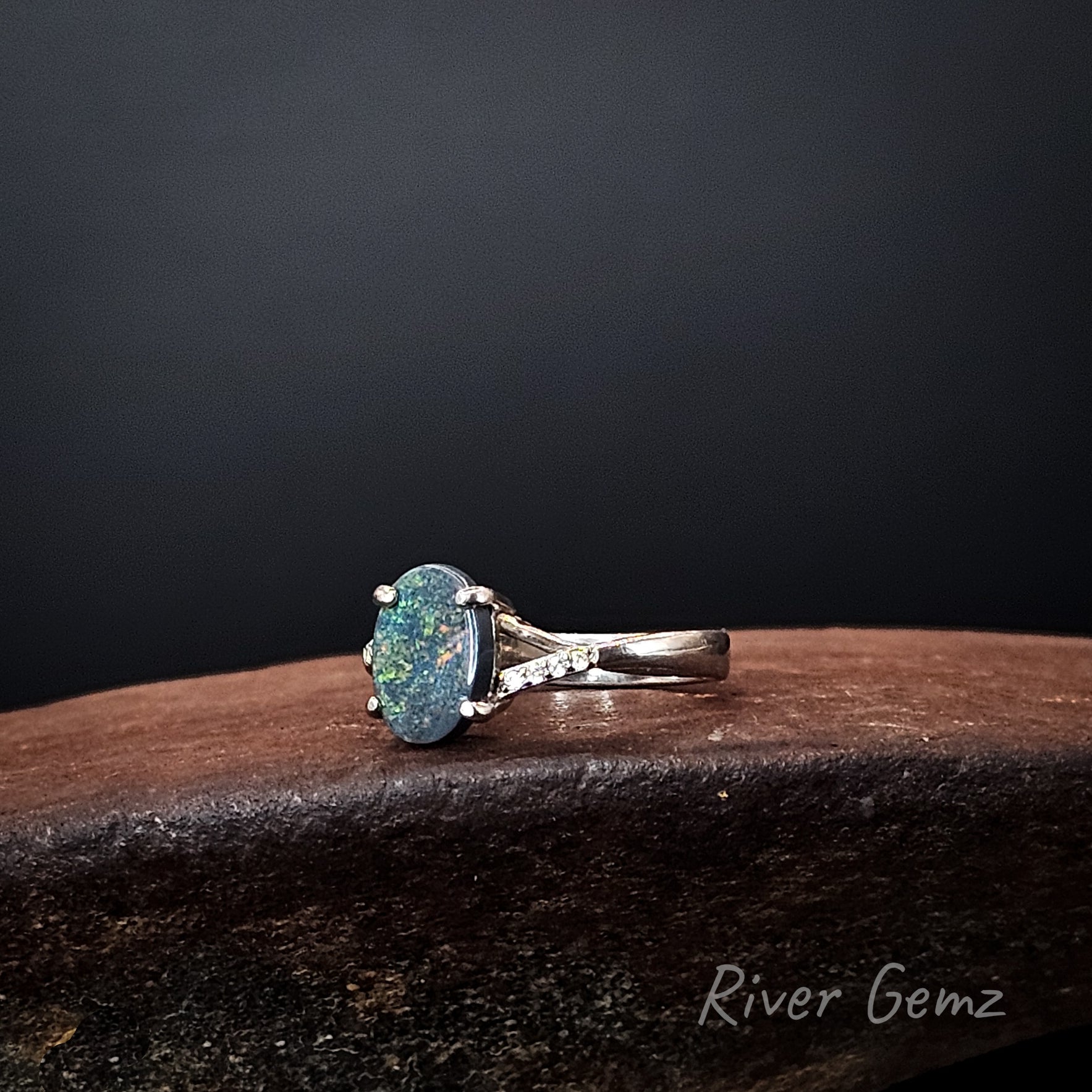 Multi-coloured black opal claw set in sterling silver ring with white topaz stone accents.