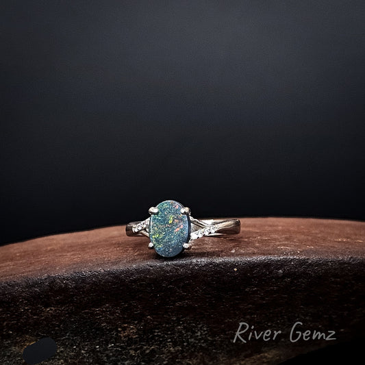 Oval shaped black opal with multi-colours claw set in silver ring.