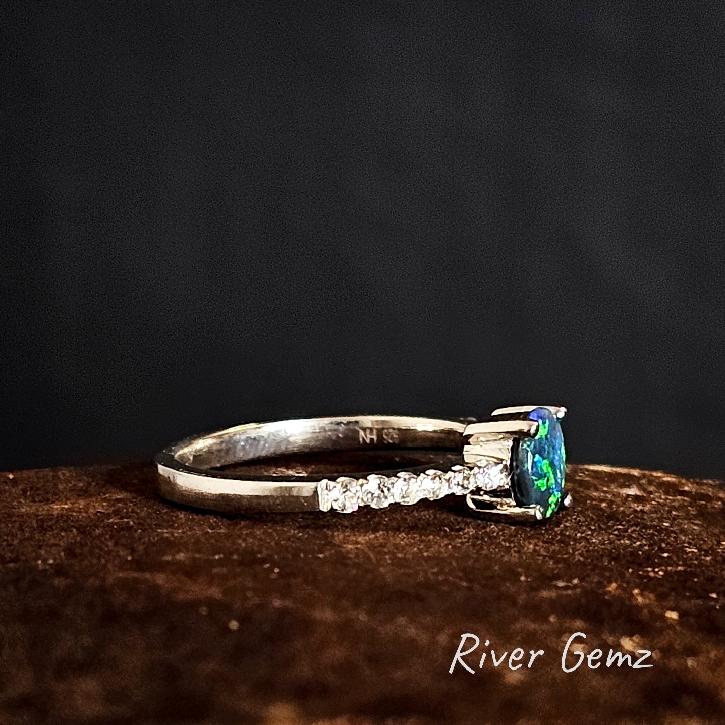 Side view of the ring showing the 925 stamp to indicate sterling silver with a green gemstone on a dark background, branded 'River Gemz'.