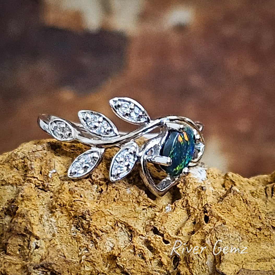 The white topaz in the leaves together with the bright silver contrast against the black opal in the silver ring.