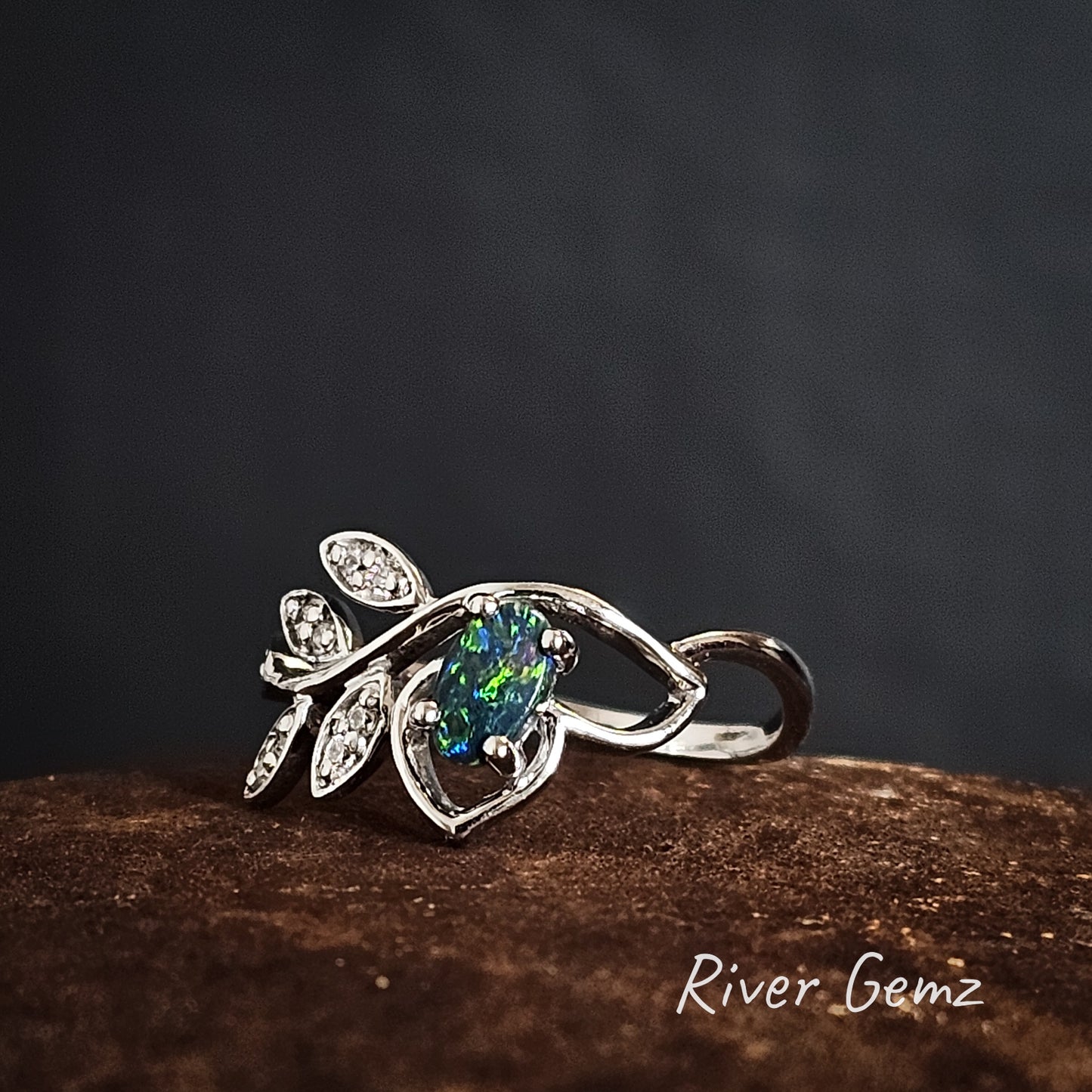 Silver ring with an opal and topaz stones on a dark background, branded 'River Gemz'.