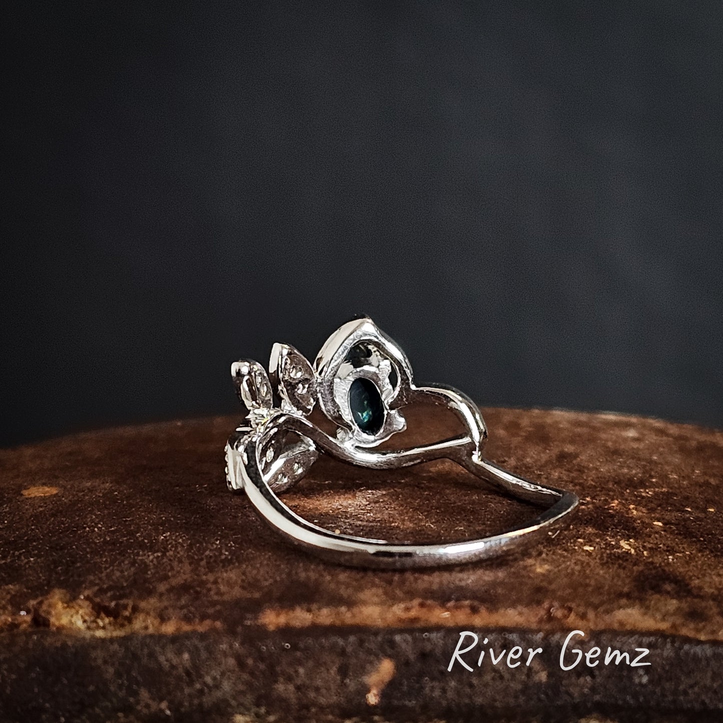 Rear view of silver ring showing the black base of the black opal on a dark background, featuring 'River Gemz' branding.