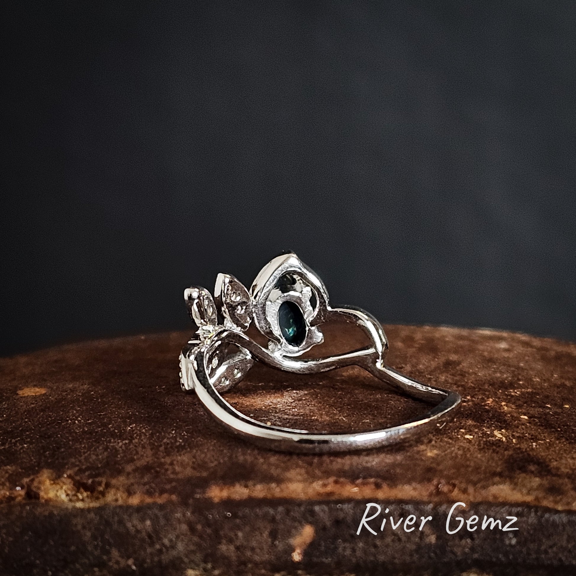 Rear view of silver ring showing the black base of the black opal on a dark background, featuring 'River Gemz' branding.