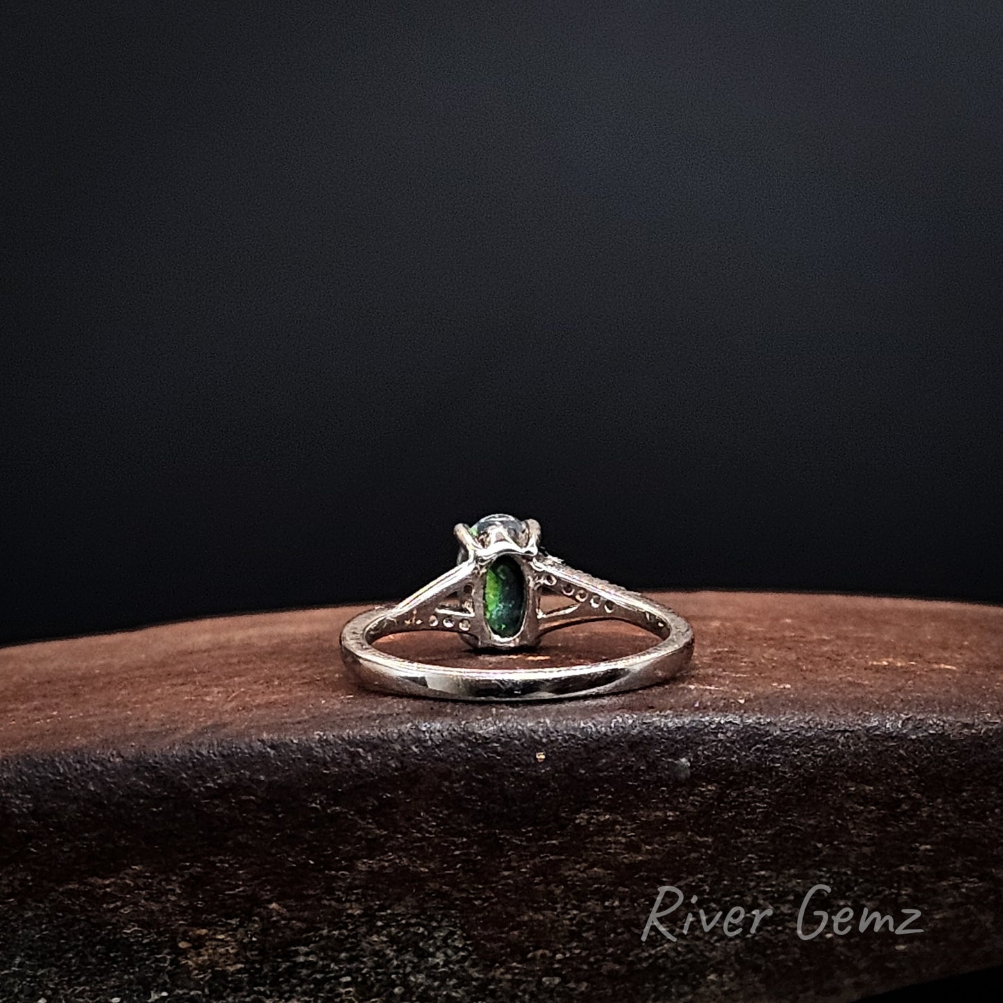 Rear view shows the dark base tone of the black opal set in the silver ring.