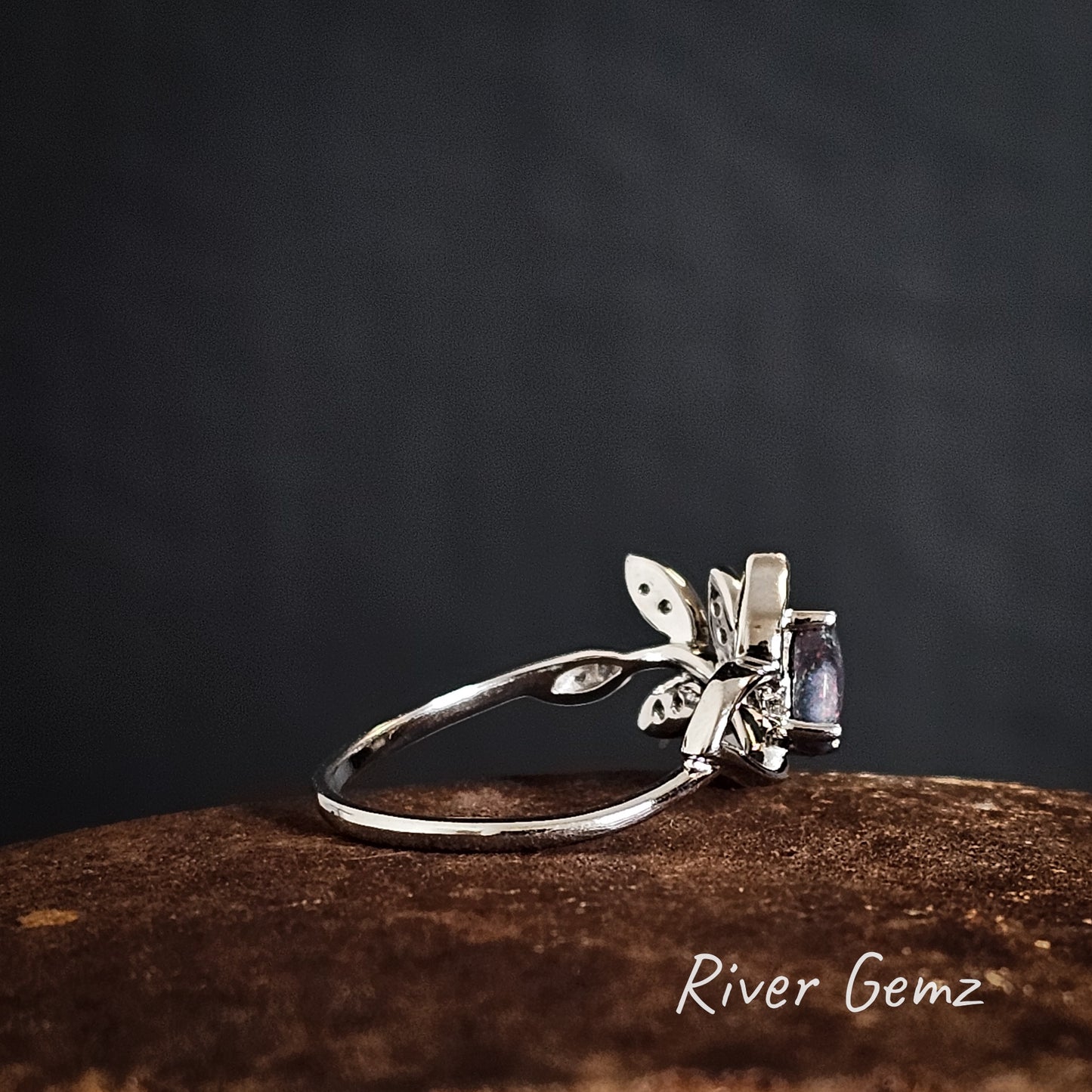 Side view of the silver ring shows the thickness of the black opal on a dark background, featuring 'River Gemz' branding.