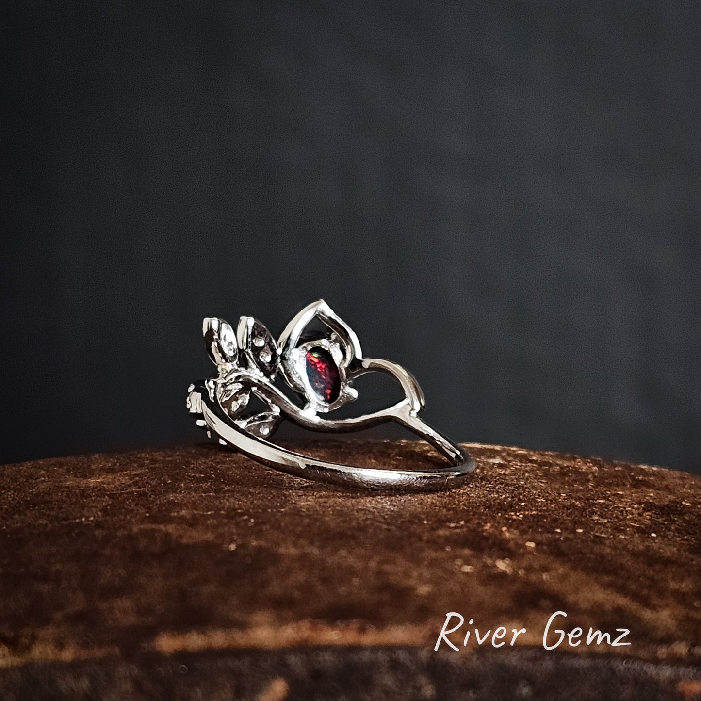Rear view of the silver ring shows the red colour of the black opal continues through the stone on a iron shoe anvil, branded 'River Gemz'.