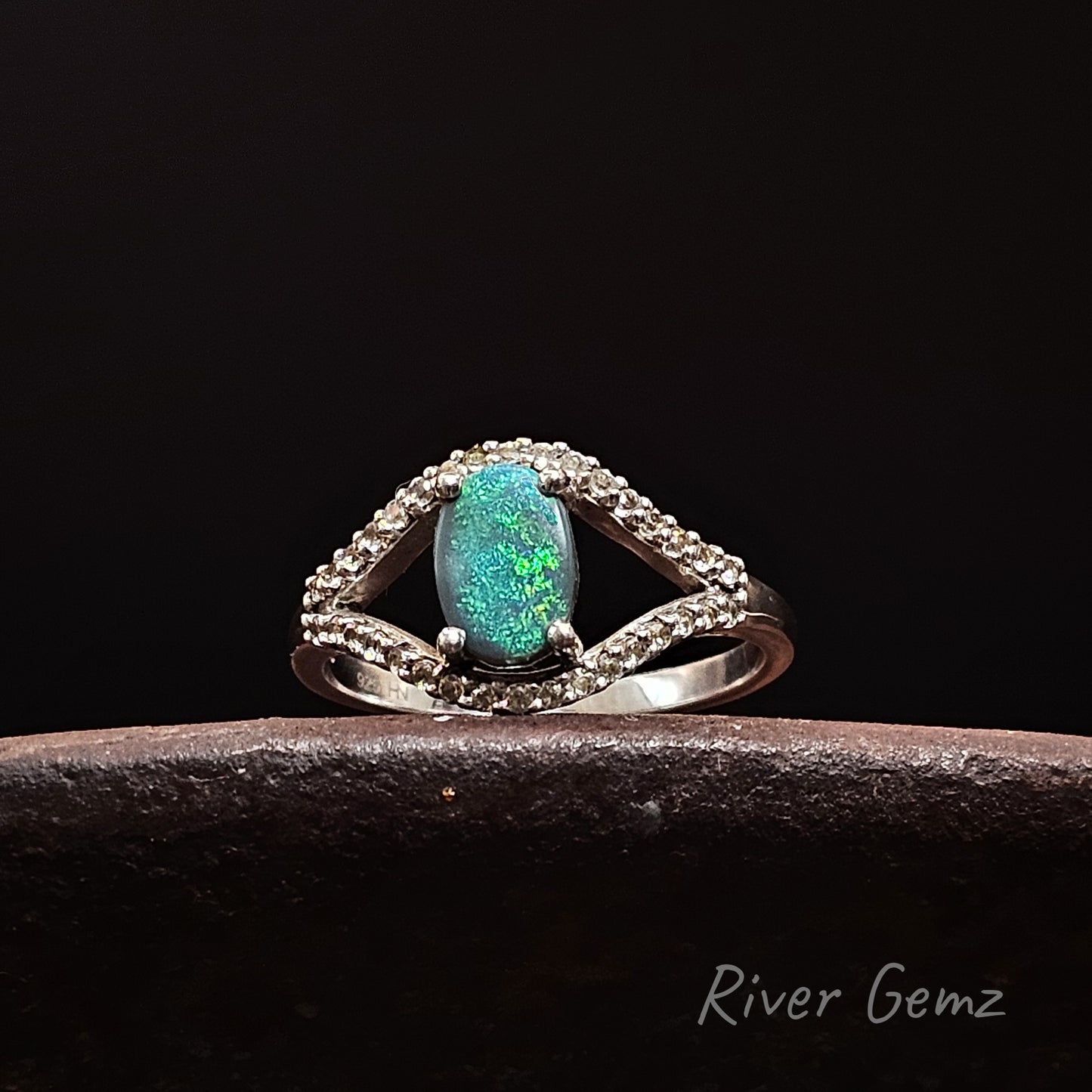 Silver ring with a green opal stone and white topaz stones on a dark background, branded 'River Gemz'.
