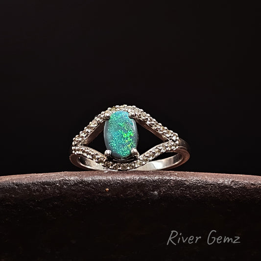 Silver ring with a green opal stone and white topaz stones on a dark background, branded 'River Gemz'.