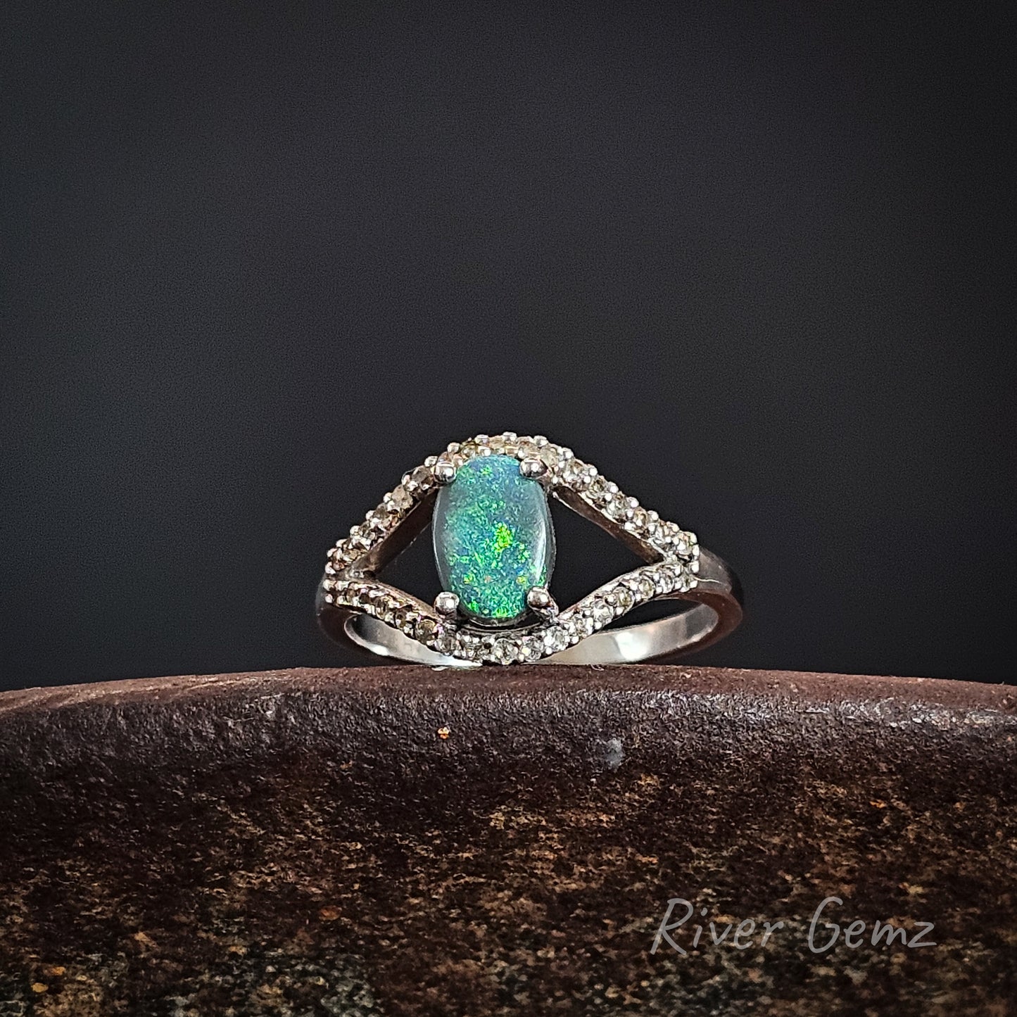 Silver ring with a green black opal on a dark background