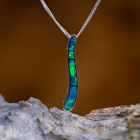 Three approximately same sized blue-green coloured opals are channel set in this long pendant. No bail needed in this modern design with the chain passing through seemlessly in the design. 