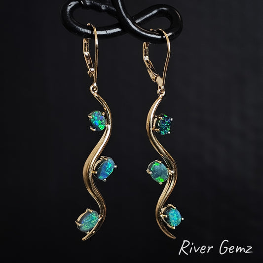 Yellow gold hook earrings with blue and green dark opals on a black background, branded 'River Gemz'.
