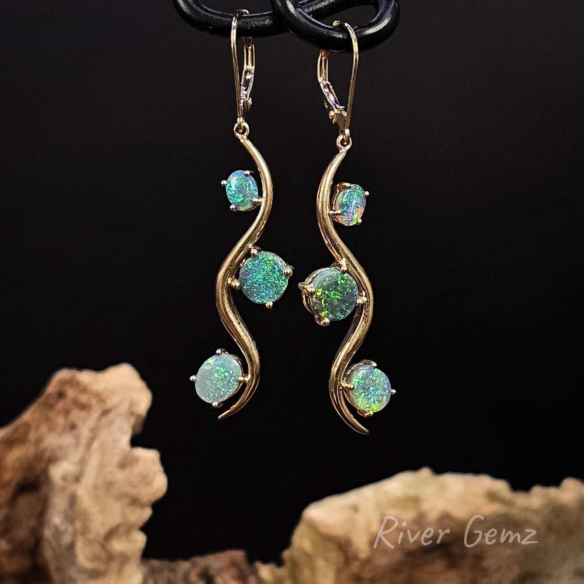 Yellow gold long earrings with continental  clasps. Three round blue and green opals claw set in each earring alternating sides of the curve design.
