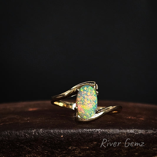 Opal ring with gold setting on a dark background, featuring the brand 'River Gemz'.