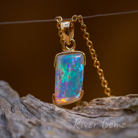 Irregular four sided shaped opal with blue,green hues tapered bail through eyelet.