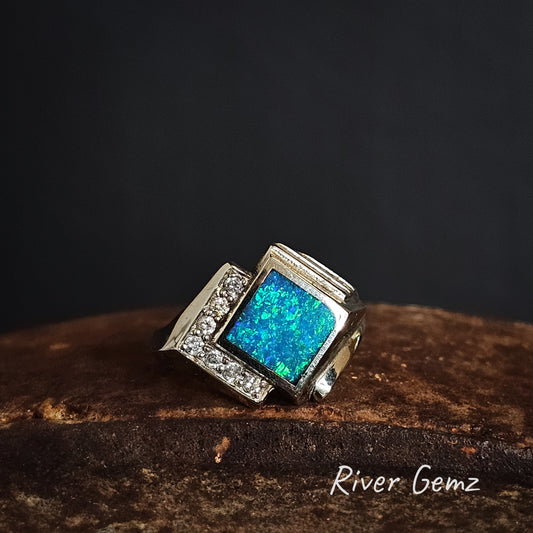 White gold ring with blue and green opal and pave diamonds on a dark background, branded 'River Gemz'.