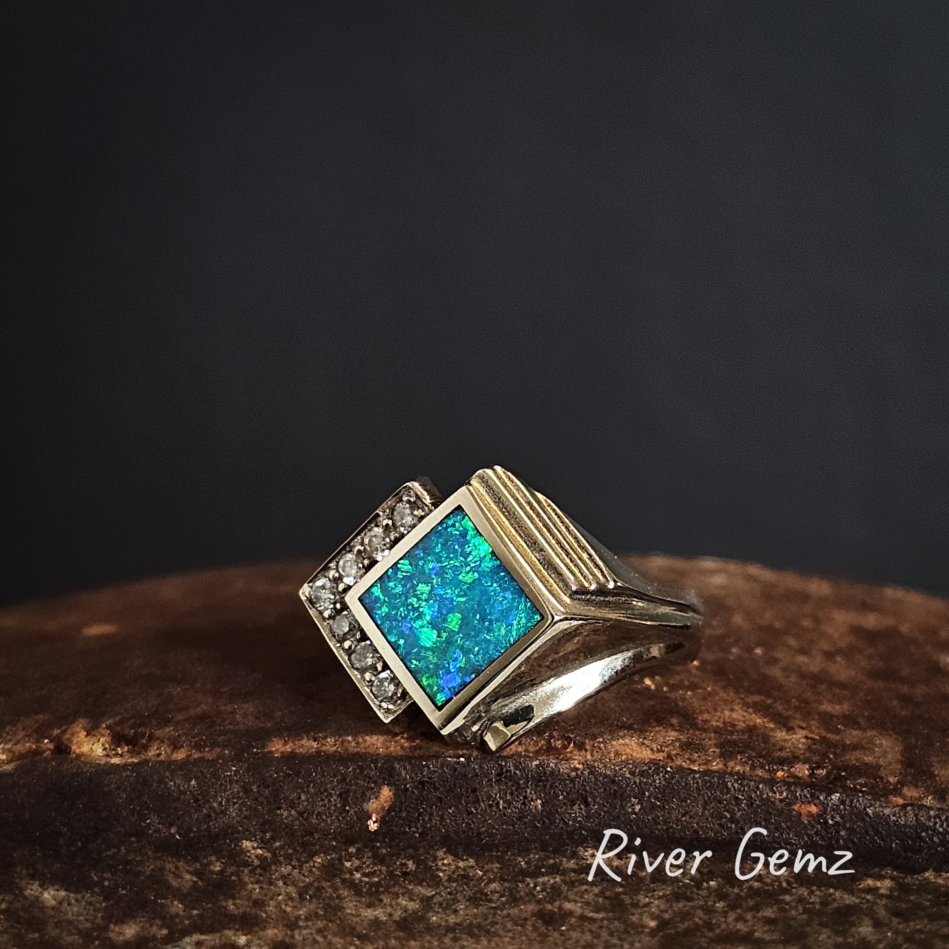 Art deco style white gold ring with blue and green crystal opal and diamond accents on a dark background, branded 'River Gemz'.