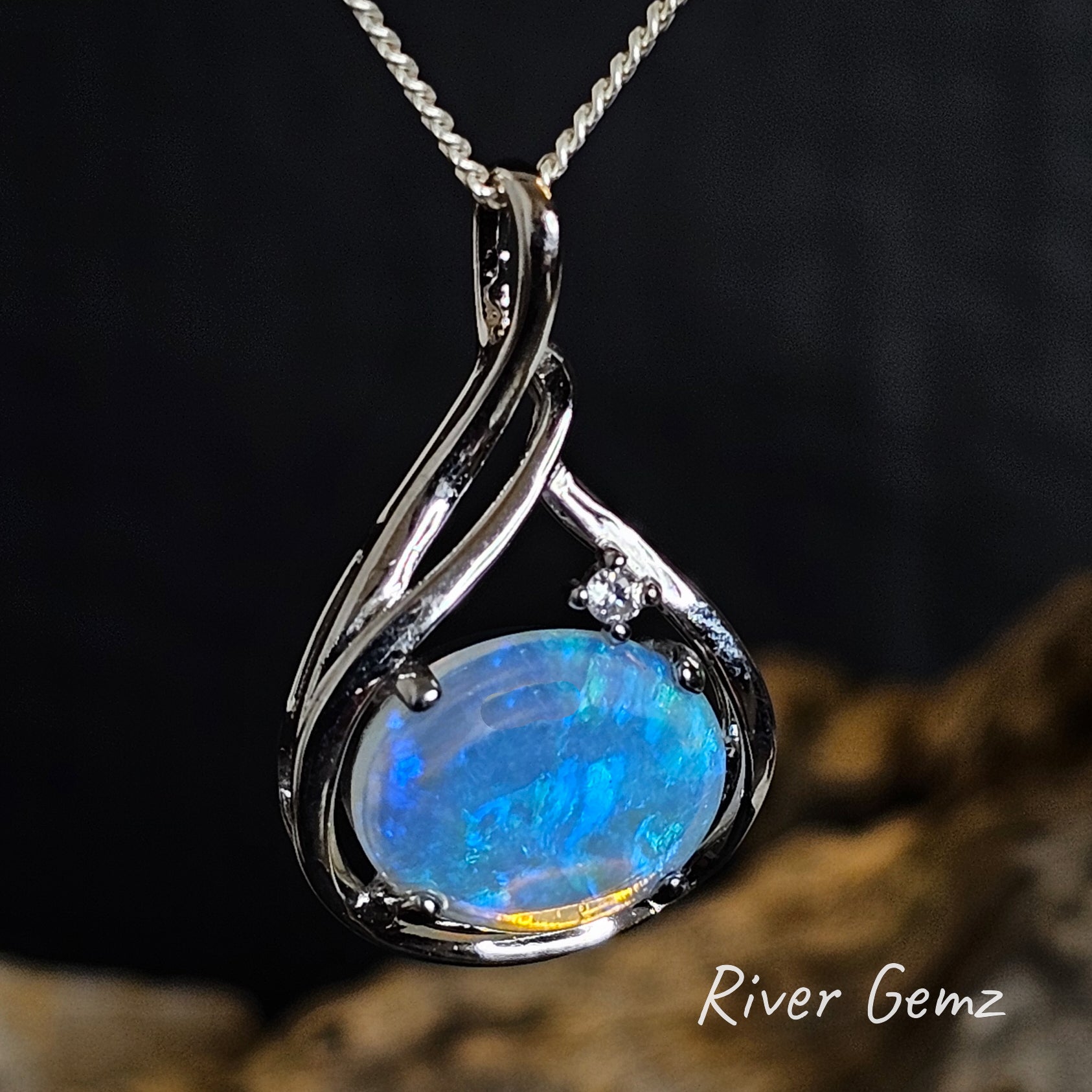 Opal pendant with silver setting on a dark background, featuring 'River Gemz' branding.