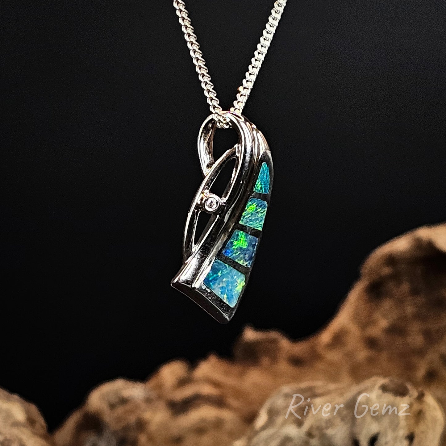 Silver necklace with 4 multicolored crystal opals on a dark background