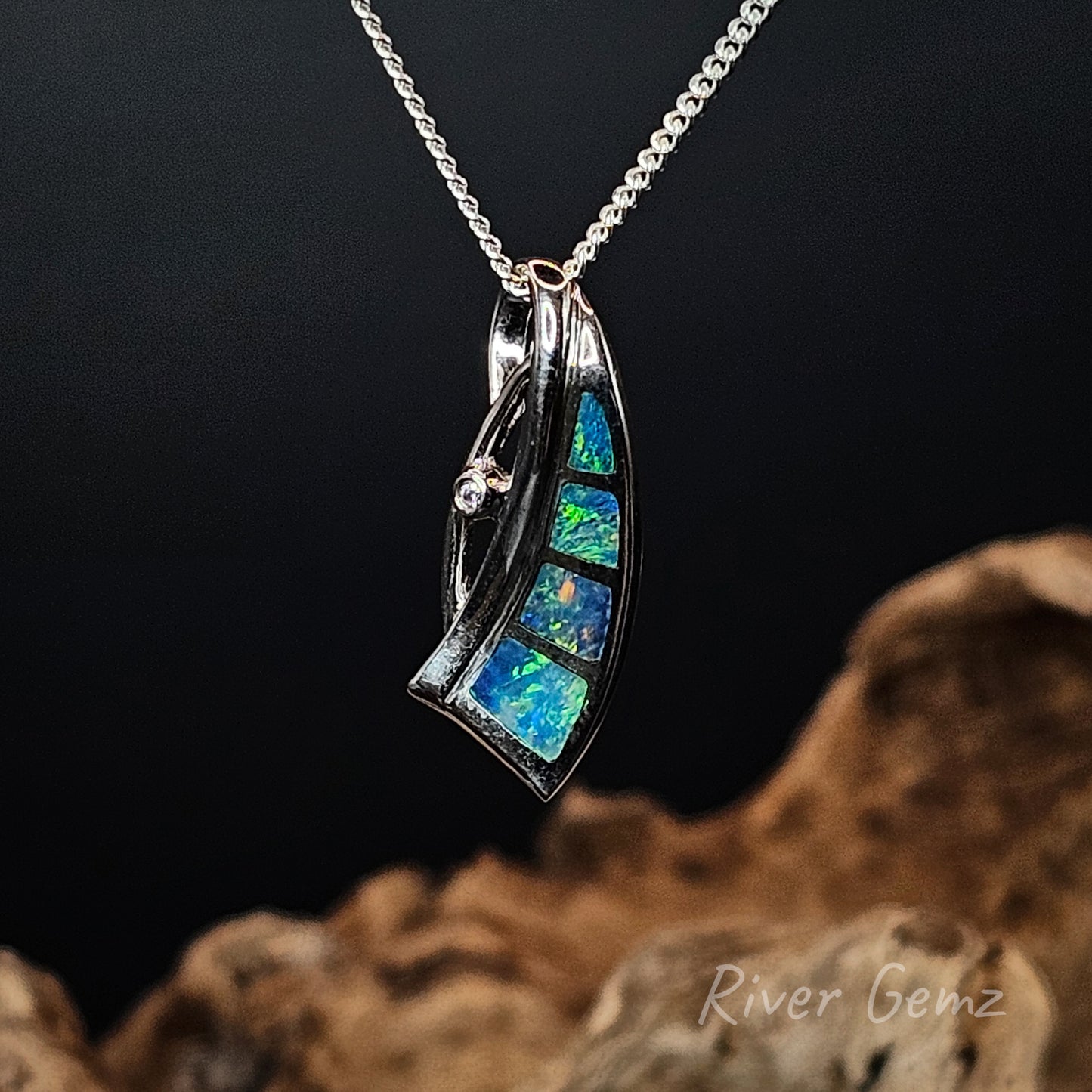 Opal pendant necklace on a chain against a dark background with 'River Gemz' branding.