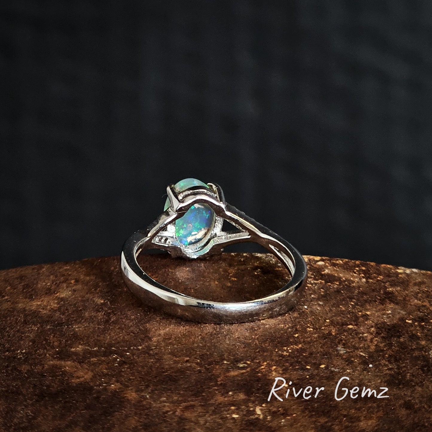 Back of silver ring with an opal stone on a dark background, branded 'River Gemz'.