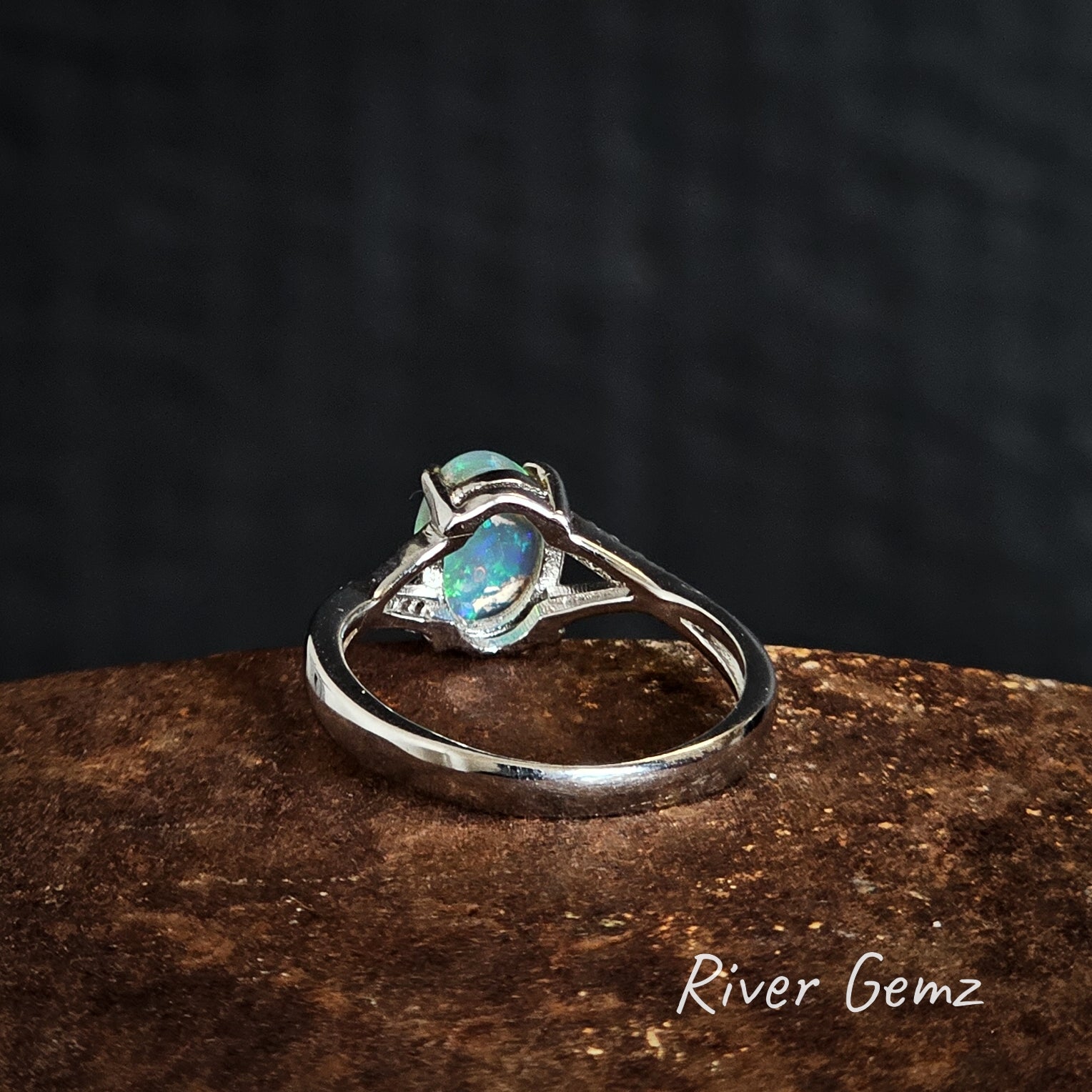 Back of silver ring with an opal stone on a dark background, branded 'River Gemz'.