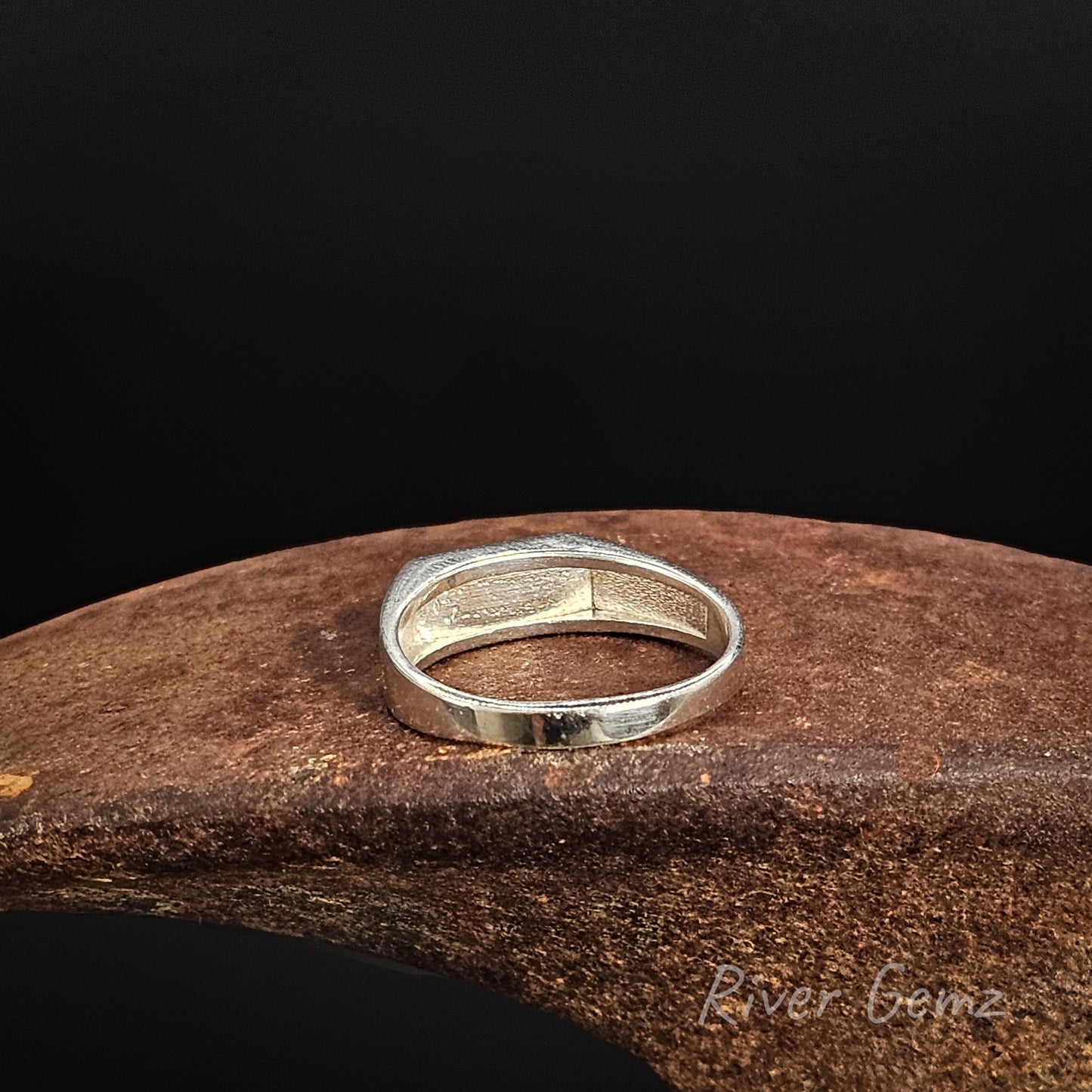 Silver ring on a wooden surface with a dark background
