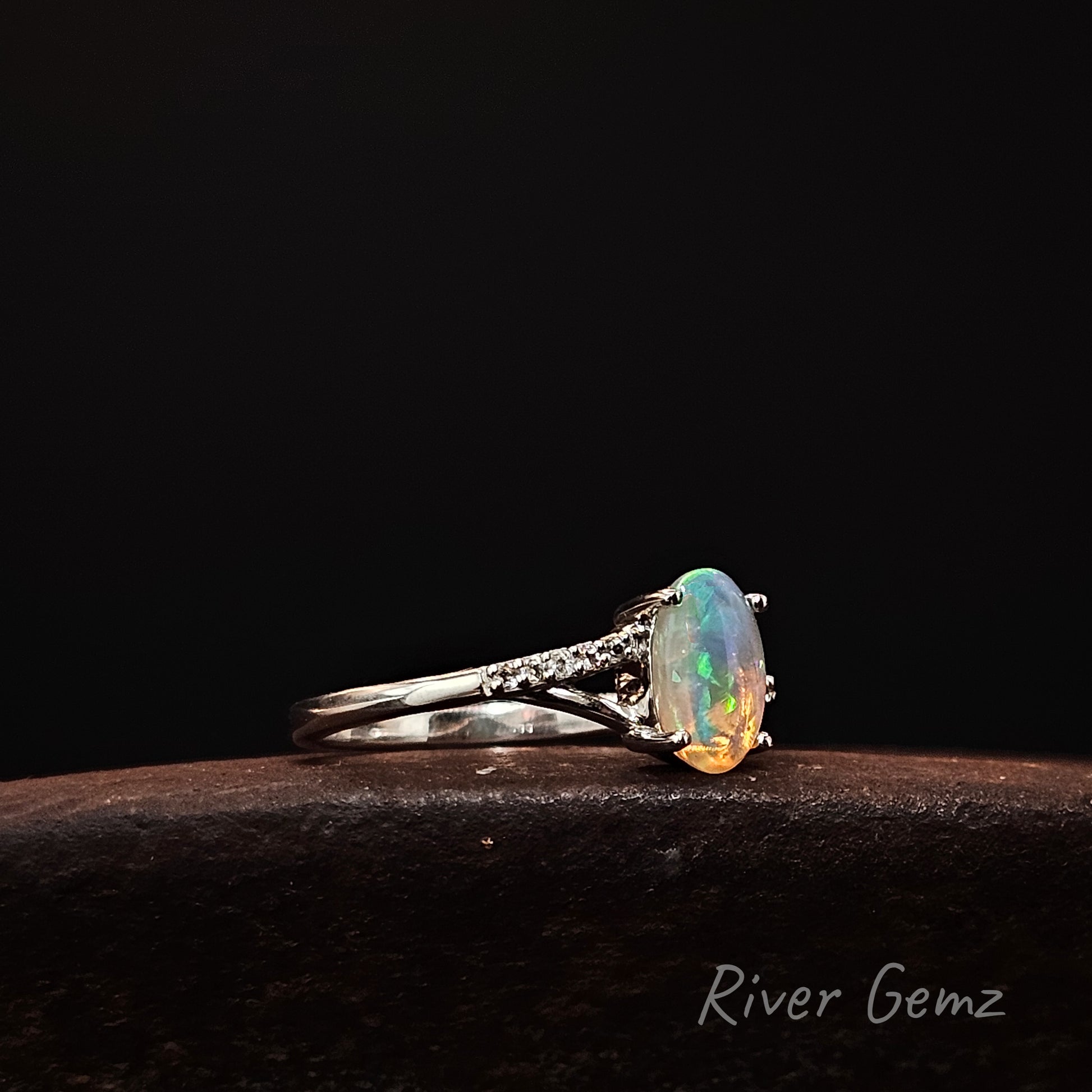 Opal ring with silver band on a dark background, featuring 'River Gemz' branding.