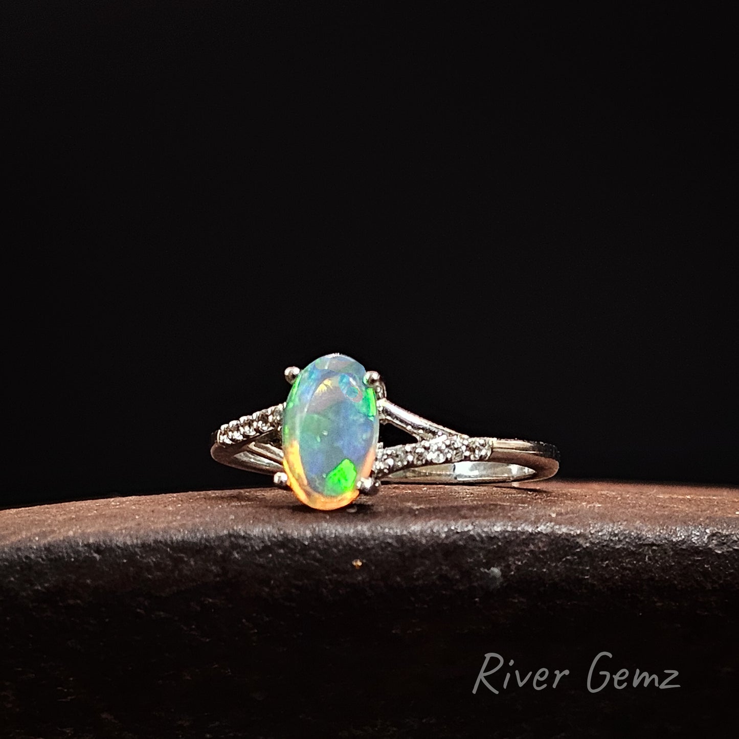 Opal ring with silver band on a dark background, featuring 'River Gemz' branding.