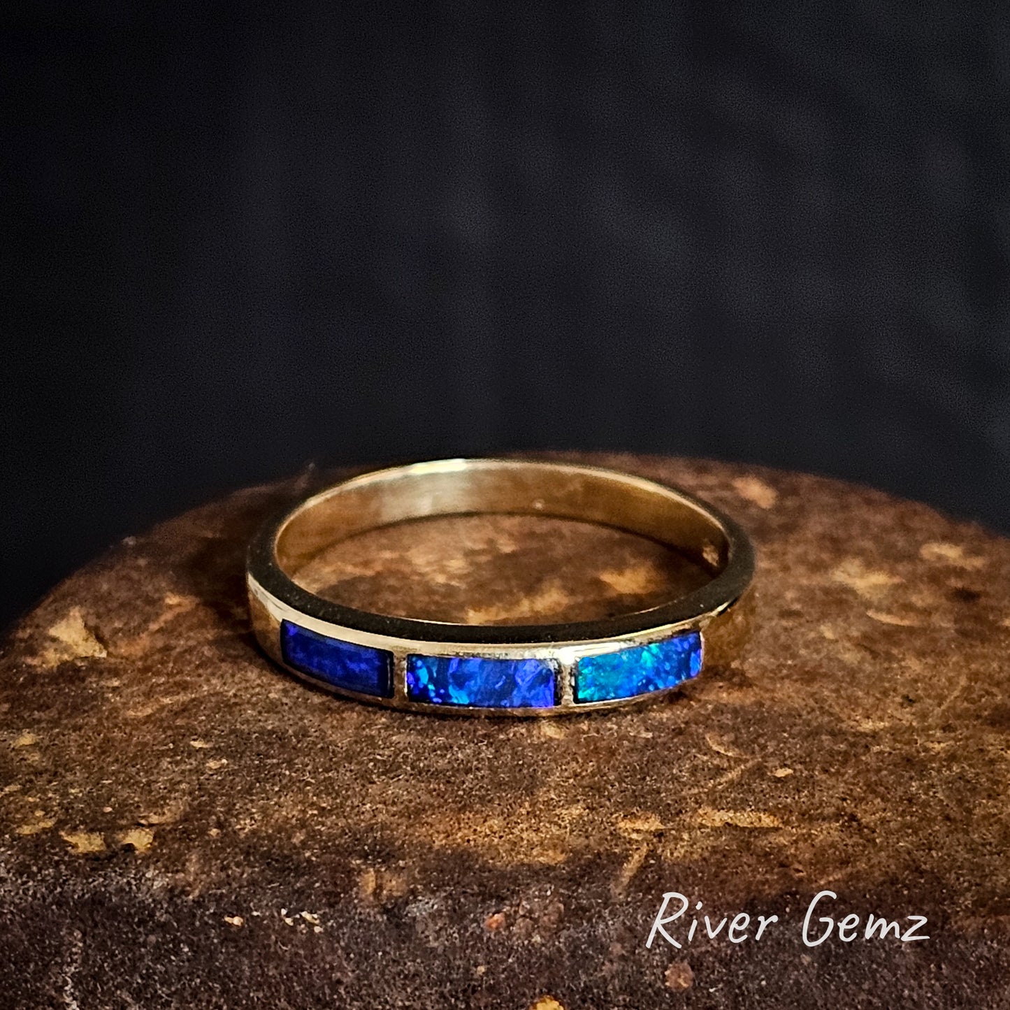 Gold ring with 3 blue opals on a dark background, featuring 'River Gemz' branding.
