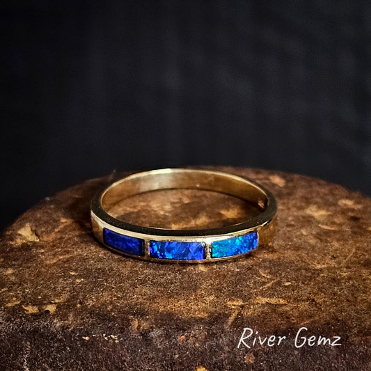 Gold ring with 3 blue opals on a dark background, featuring 'River Gemz' branding.