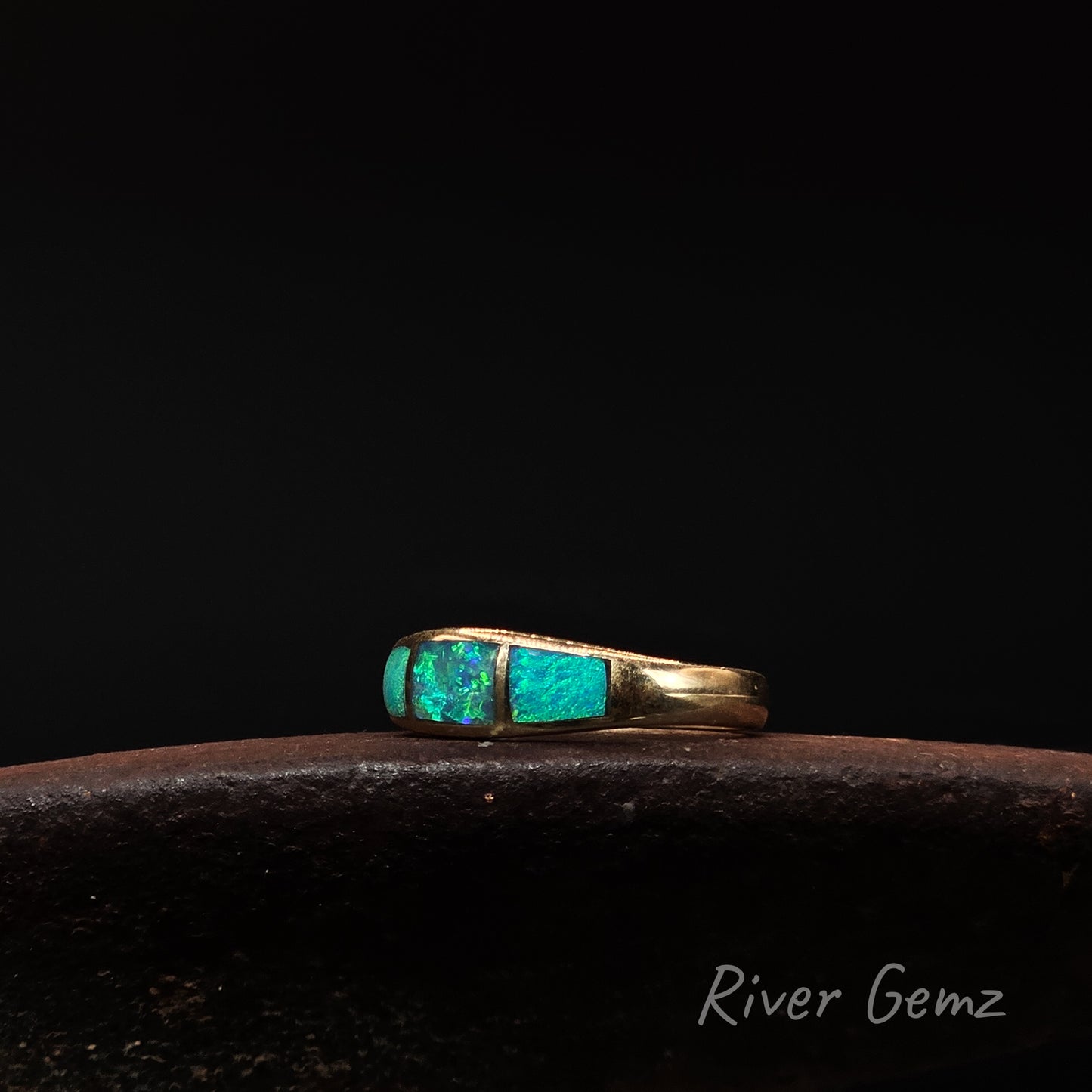 Gold ring with turquoise stones on a dark background, branded 'River Gemz'.