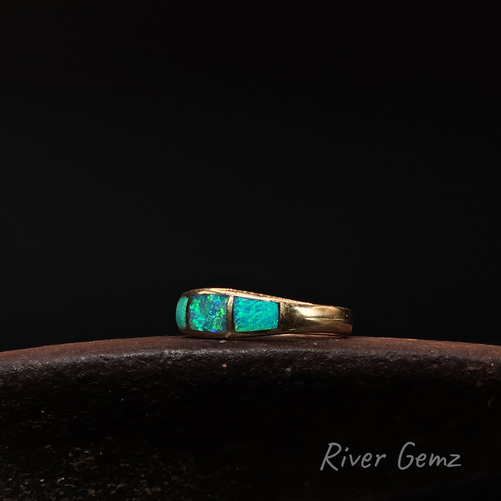 Gold ring with turquoise stones on a dark background, branded 'River Gemz'.