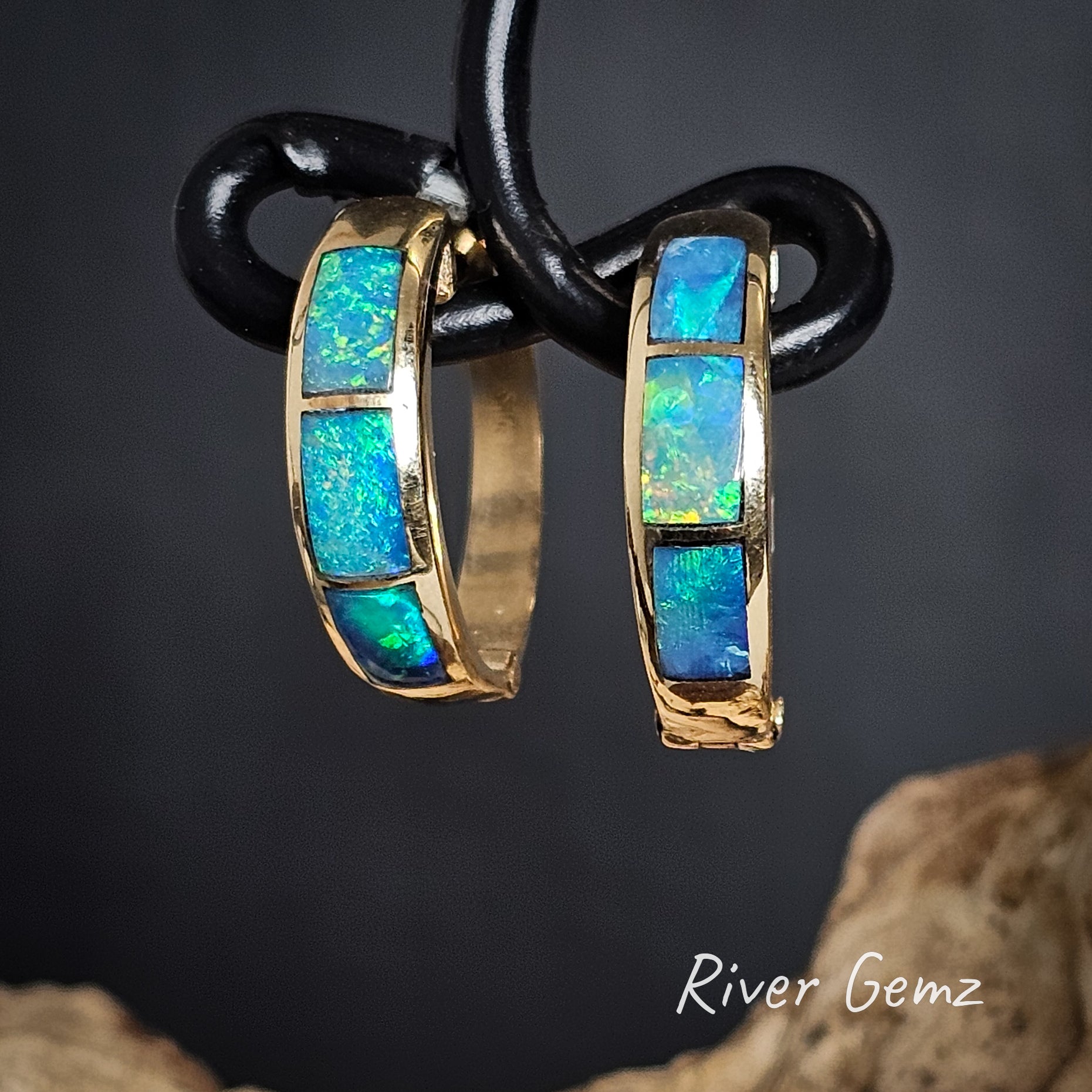 Yellow gold loop earrings with 3 rectangular blue and green crystal opals inlaid on a dark background, branded 'River Gemz'.
