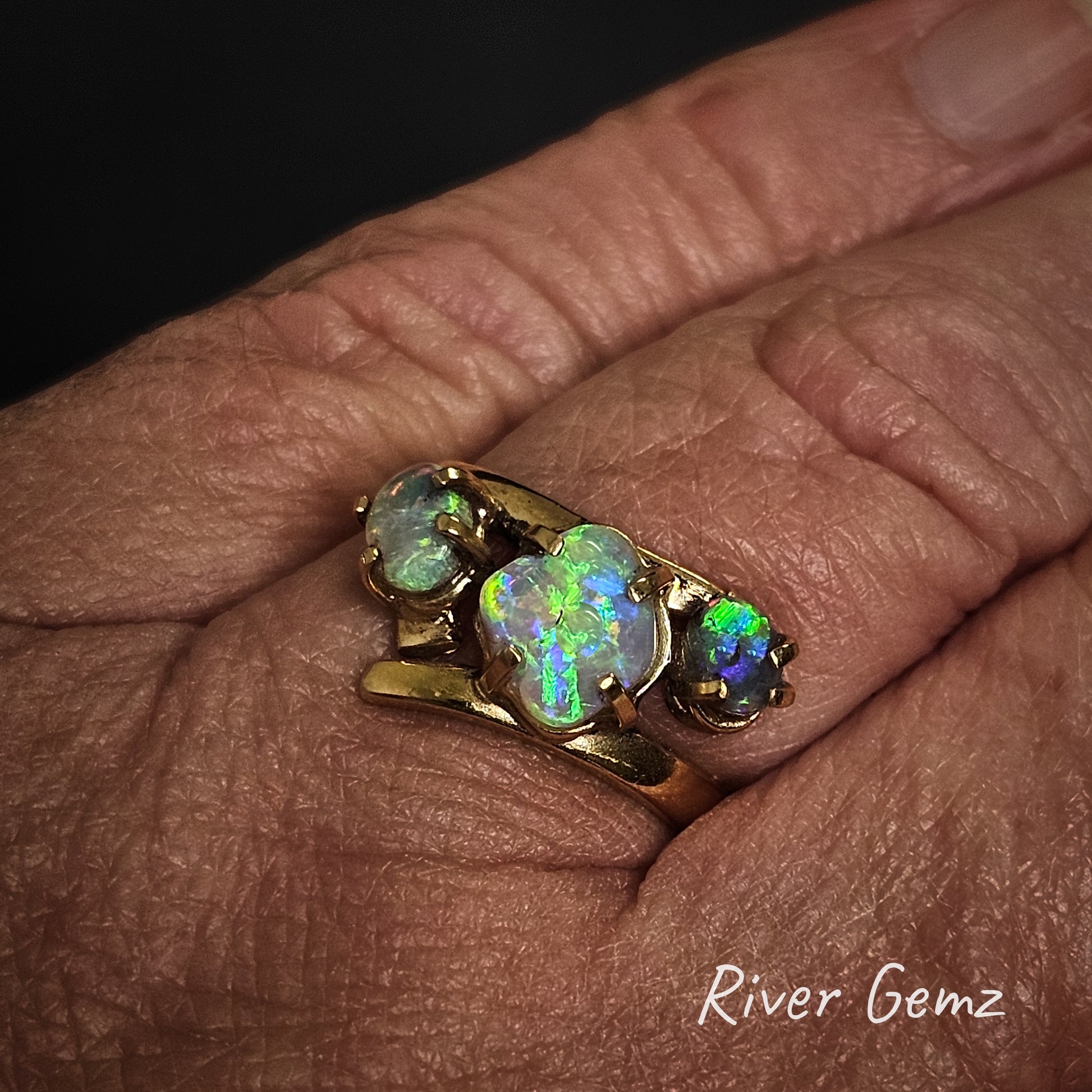 Three different shaped crystal opals claw set in yellow gold ring shown worn on left hand.