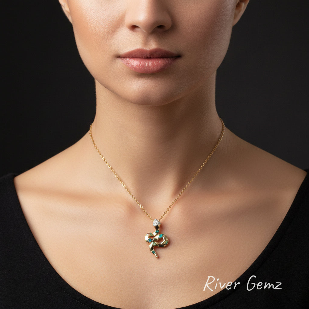 Gold snake-shaped pendant with gemstones on a chain against a dark background, branded 'River Gemz'.