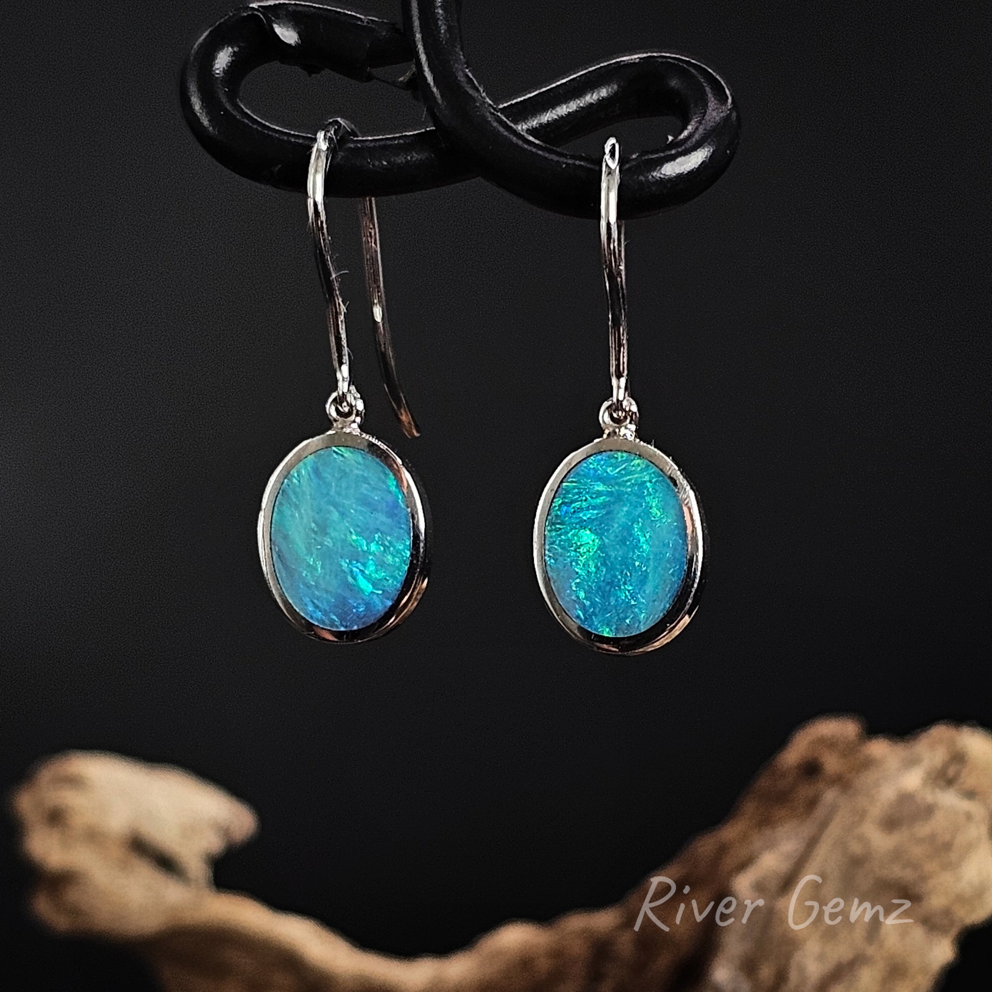 Oval shaped blue and green opals besel set in sterling silver French hook earrings.