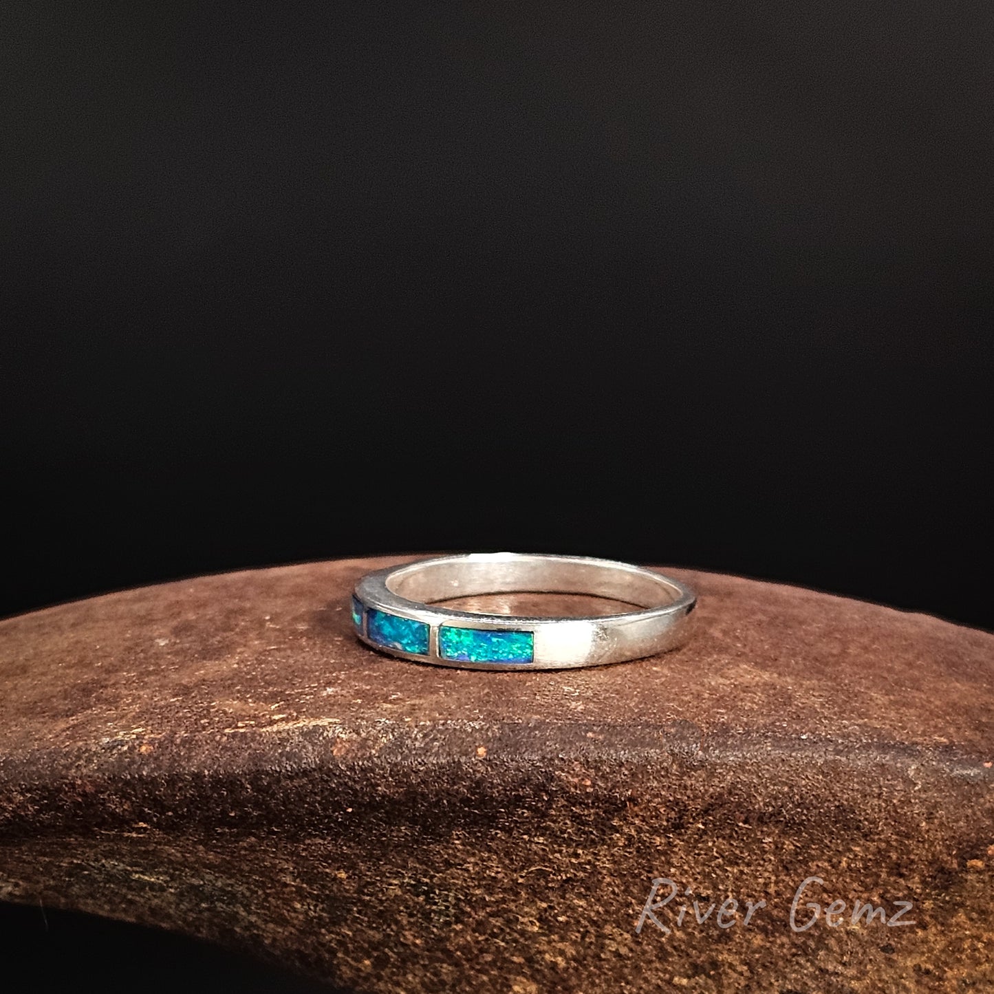 Silver ring with blue gemstones on a dark background