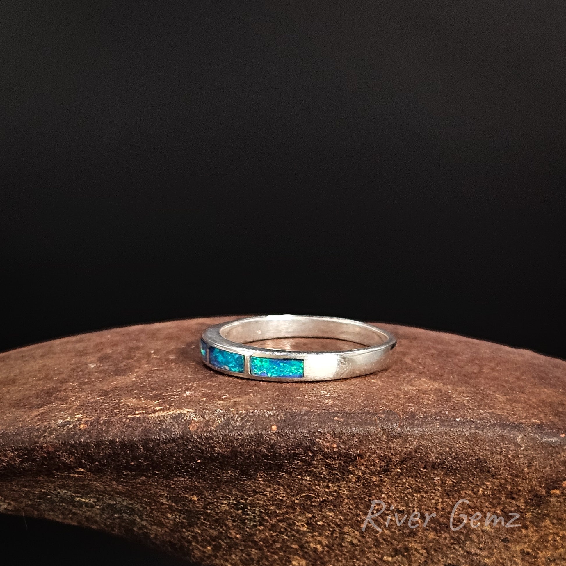 Silver ring with blue gemstones on a dark background