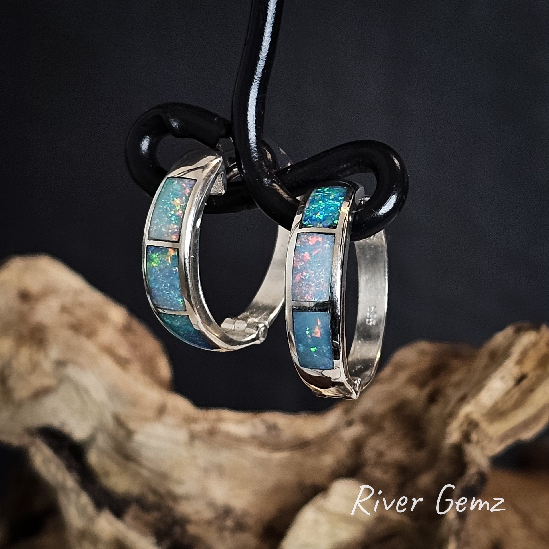 Opal hoop earrings on a black wire with 'River Gemz' branding, set against a dark background.