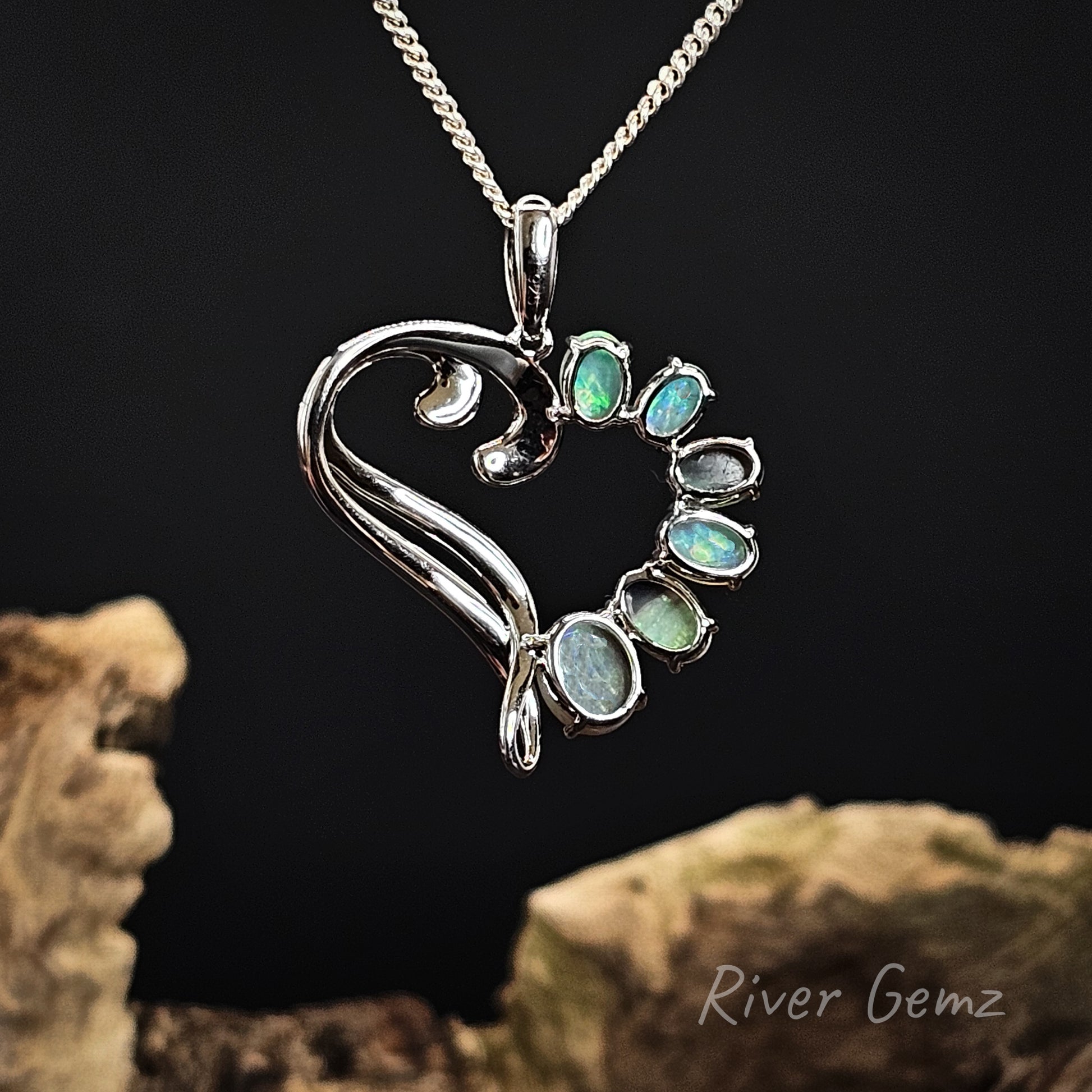Rear view of the heart-shaped silver pendant shows the light base tone of the crystal opals set within the necklace.