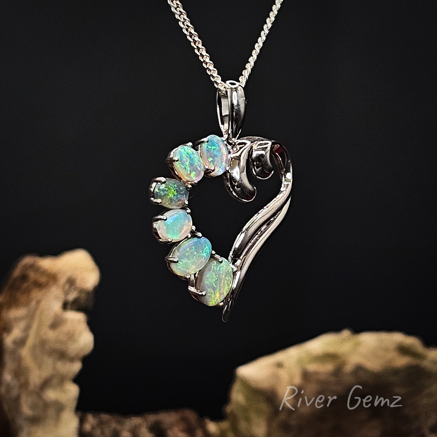 Heart-shaped opal pendant on a chain with a dark background