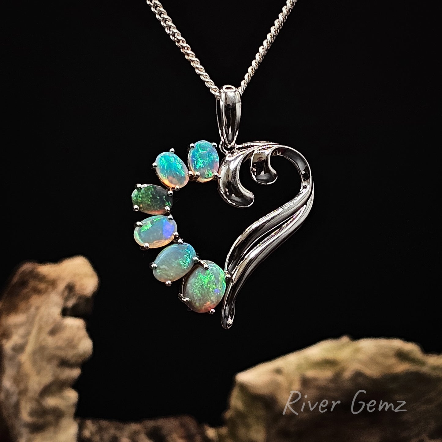 6 oval shaped light opals claw set in sterling silver pendant with a silver chain on a dark background, featuring the brand 'River Gemz'.