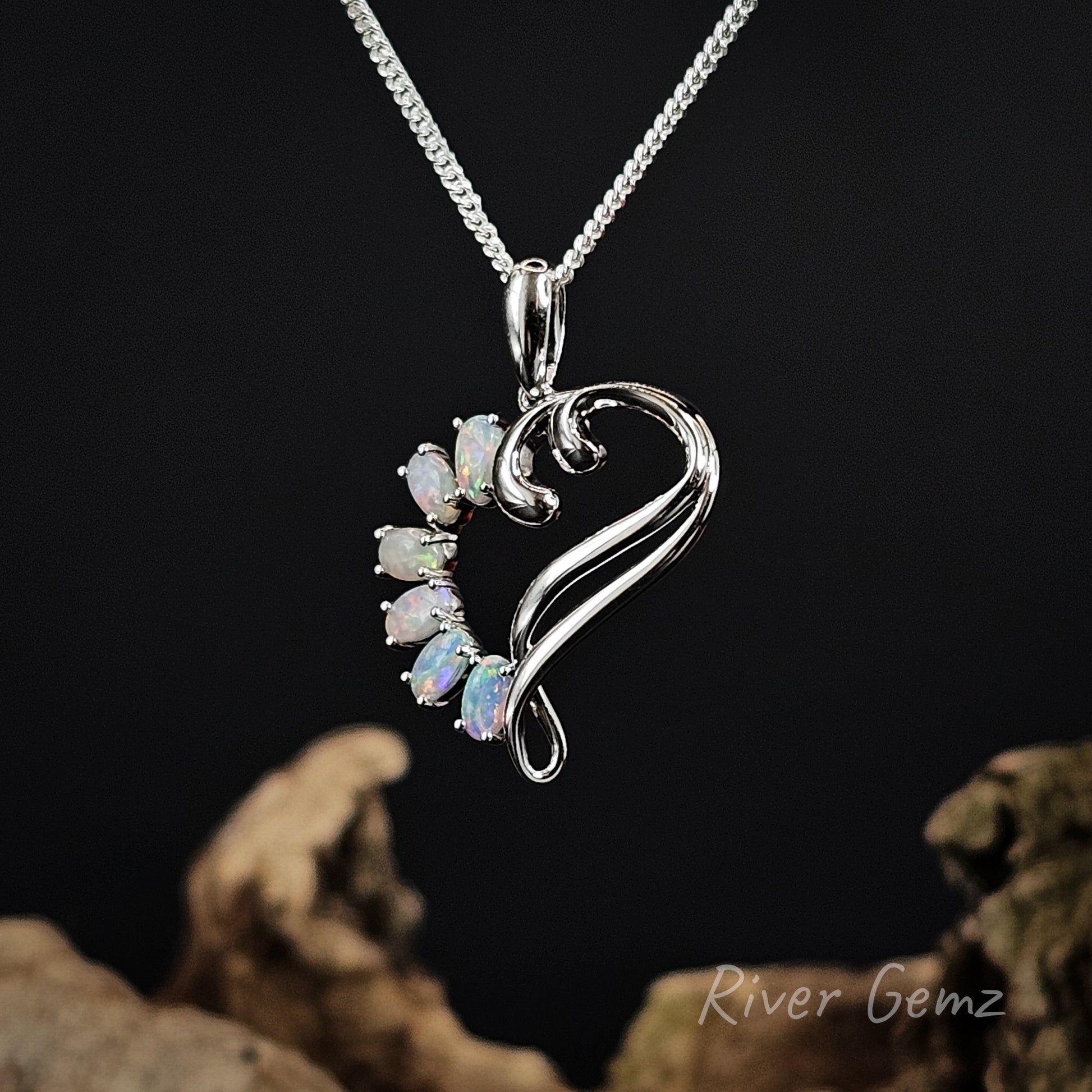 Silver pendant with gemstones on a chain against a dark background