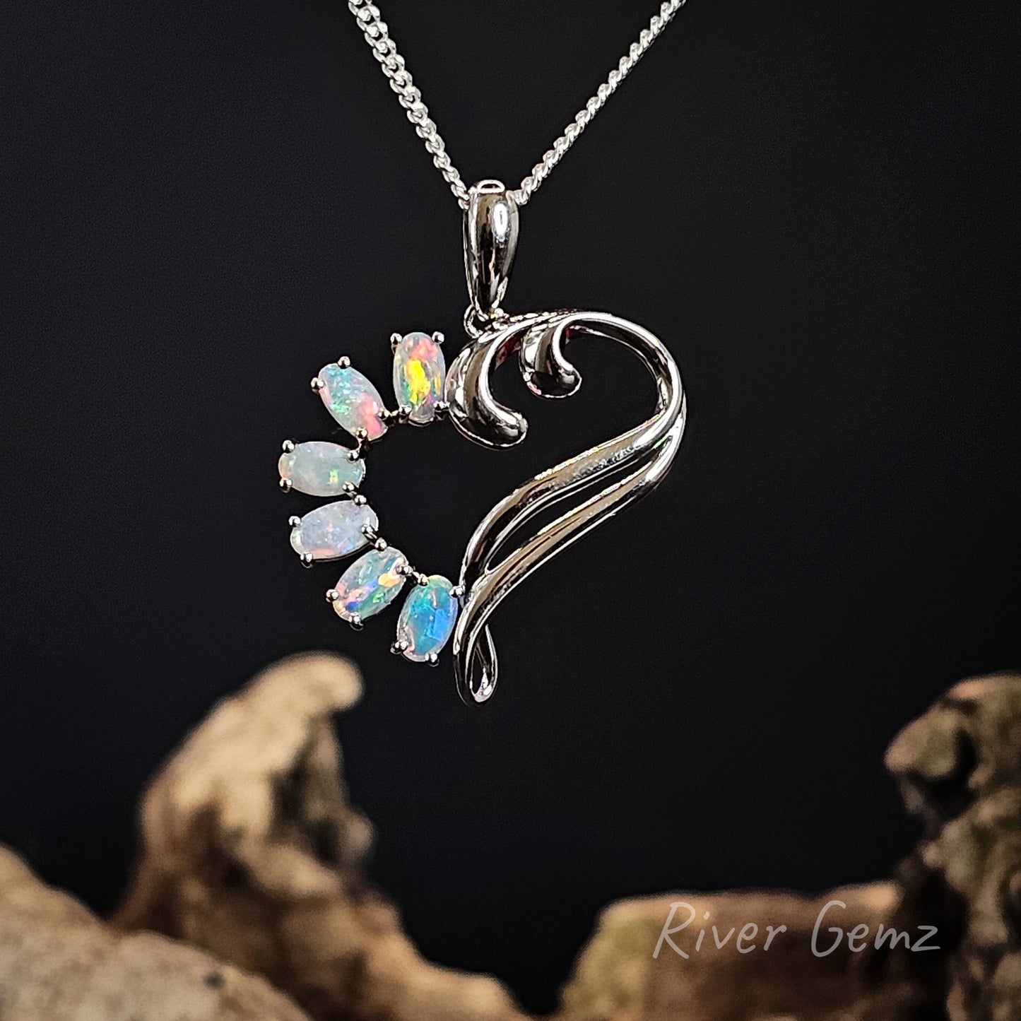 Silver pendant with opal stones on a dark background