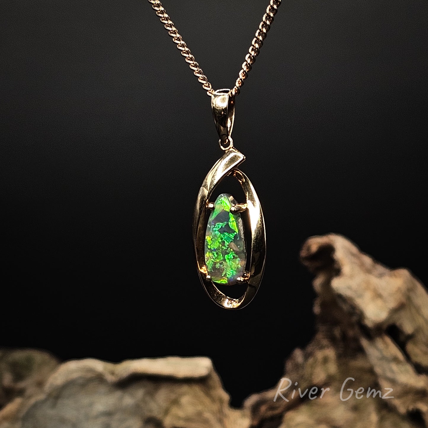 Dark opal claw set in yellow gold necklace on a dark background with 'River Gemz' branding.