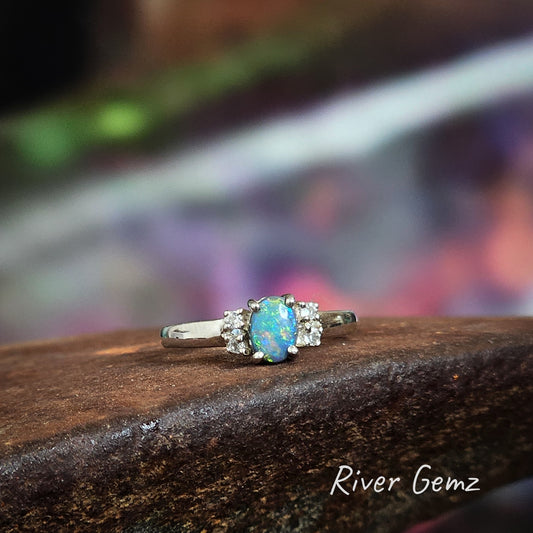 Oval shaped multi-coloured dark opal and white topaz claw set in silver ring.