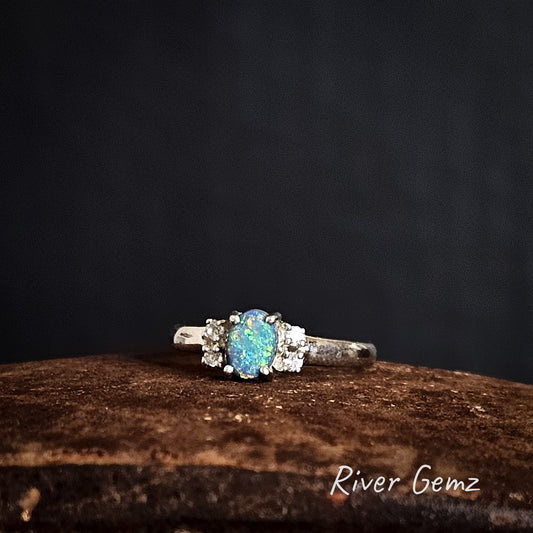 Silver ring with a blue and green opal stone on a dark background, branded 'River Gemz'.