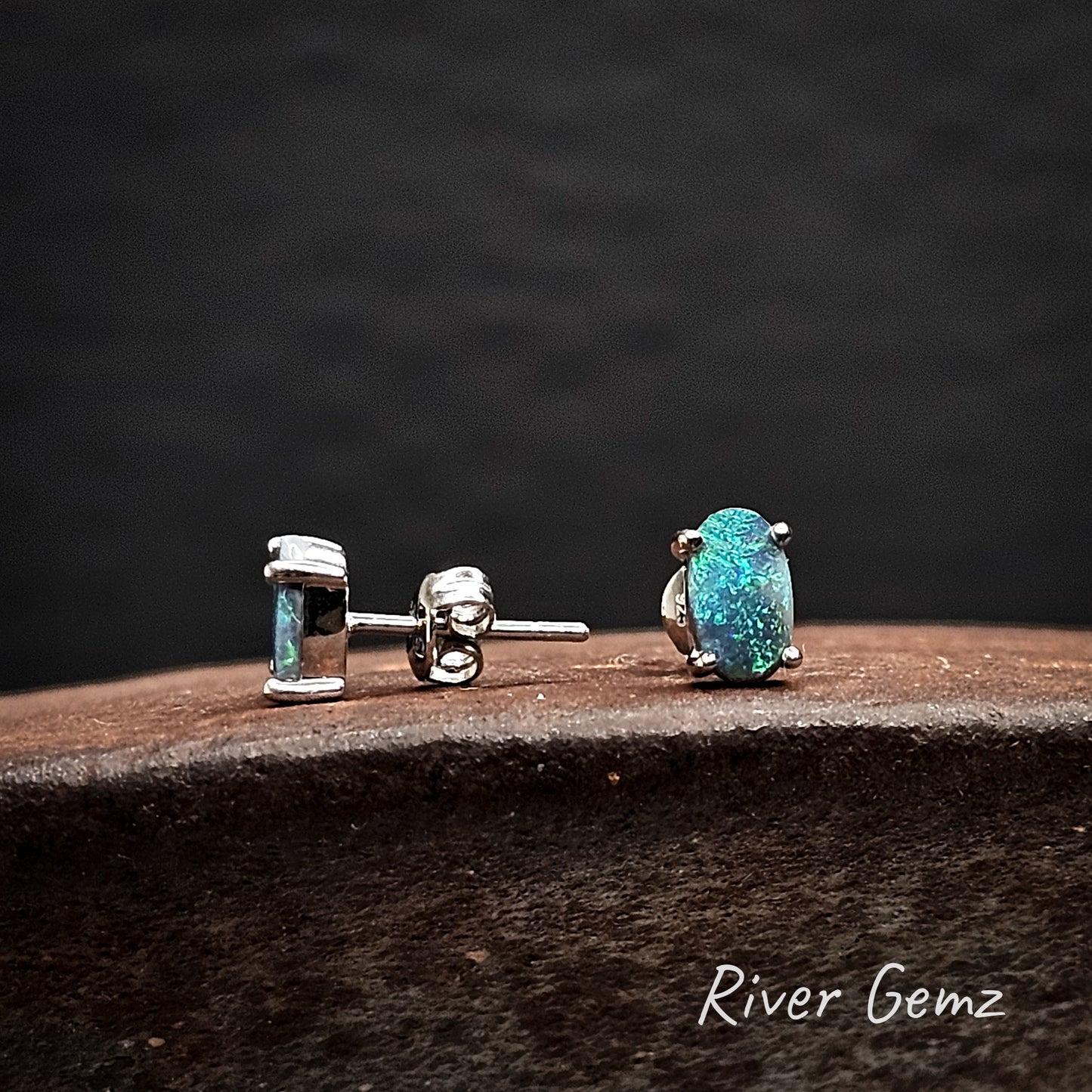 Pair of turquoise opal stud earrings on a dark surface with 'River Gemz' branding.