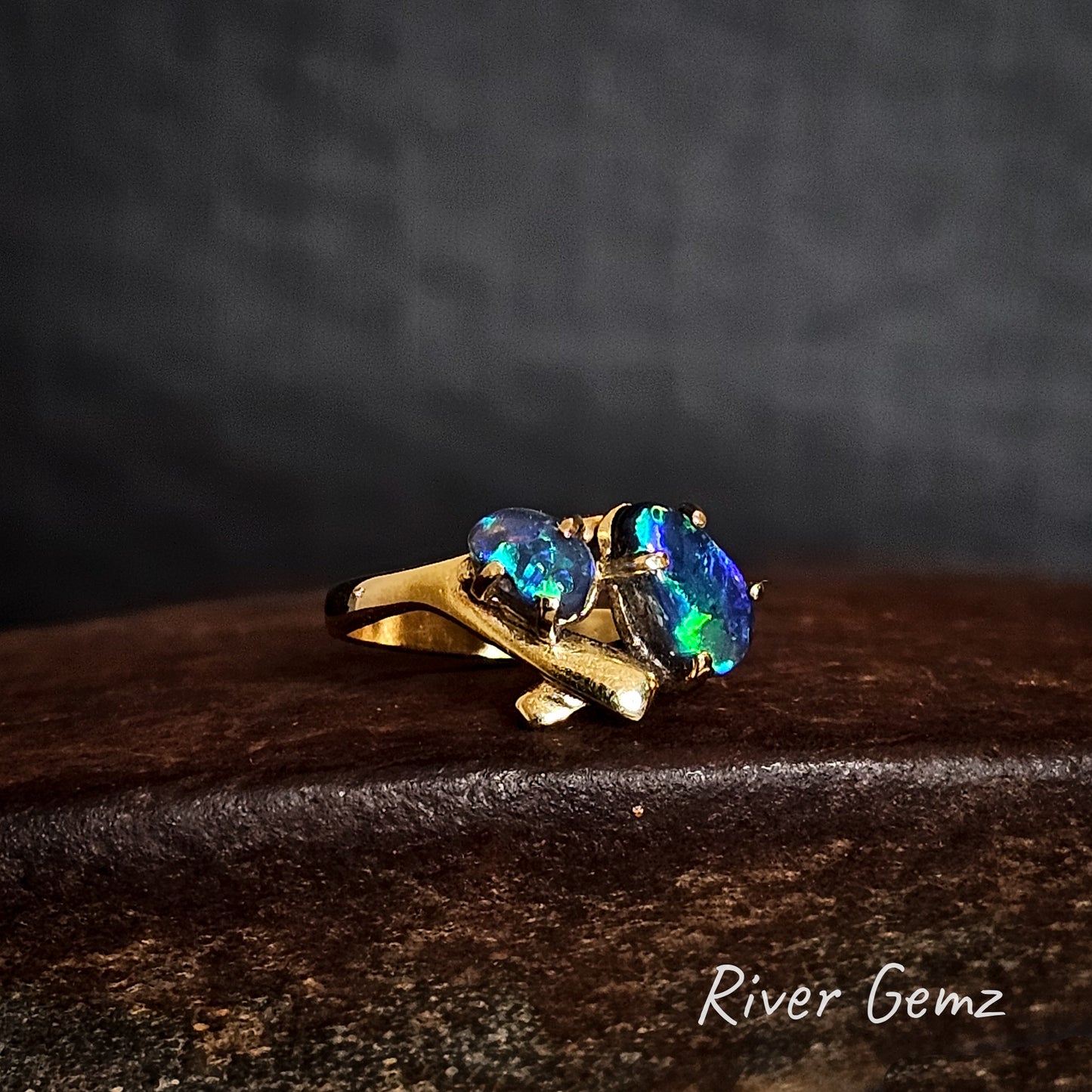 Two dark blue and green opals set in a yellow gold ring.