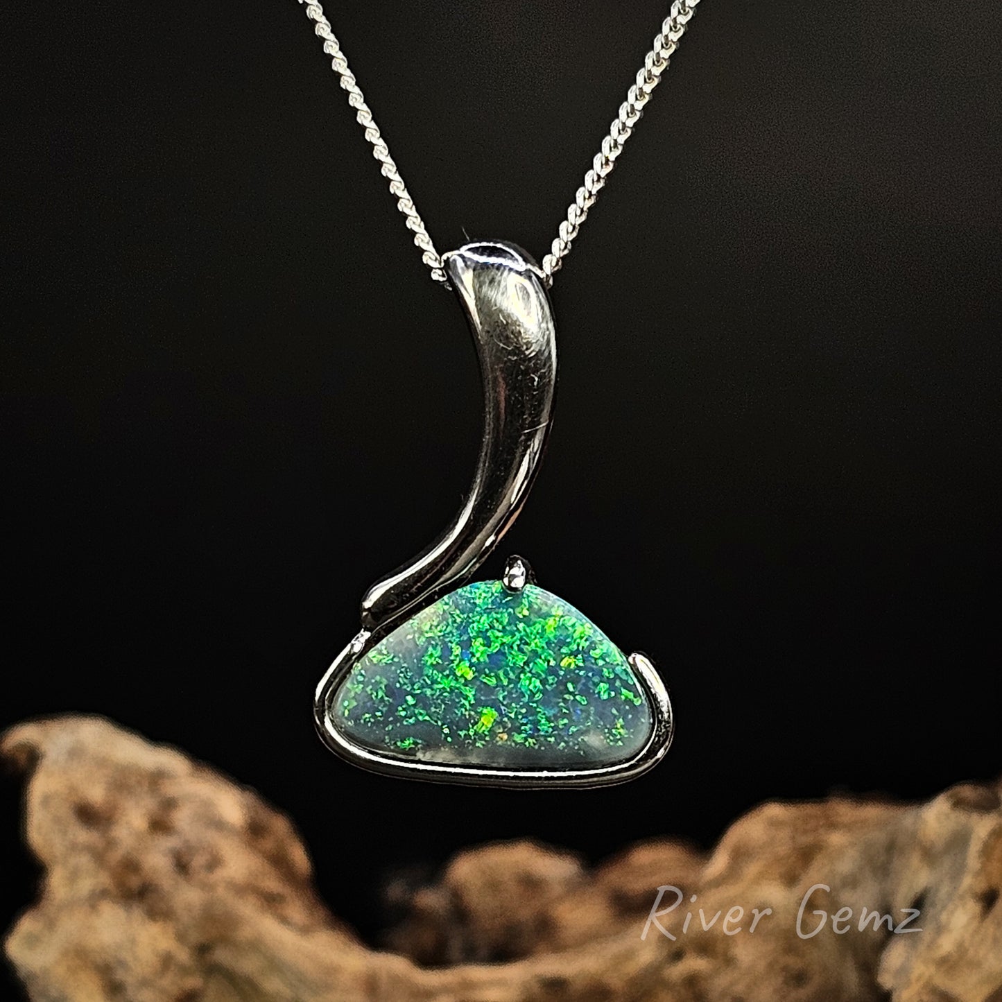 Black opal in sterling silver pendant on a chain with a dark background